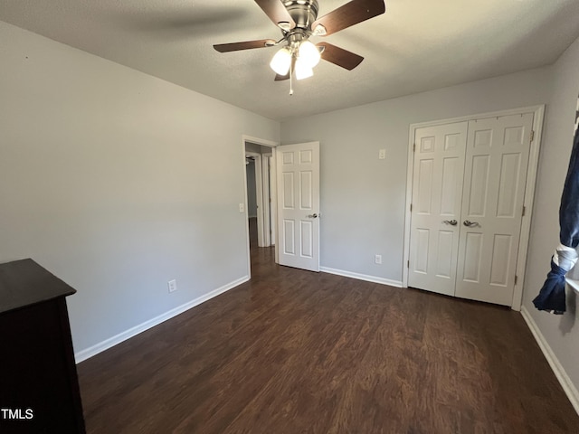 unfurnished bedroom with ceiling fan, a closet, baseboards, and dark wood finished floors