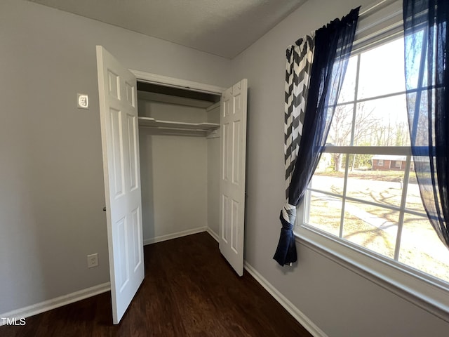 unfurnished bedroom featuring wood finished floors, baseboards, and a closet