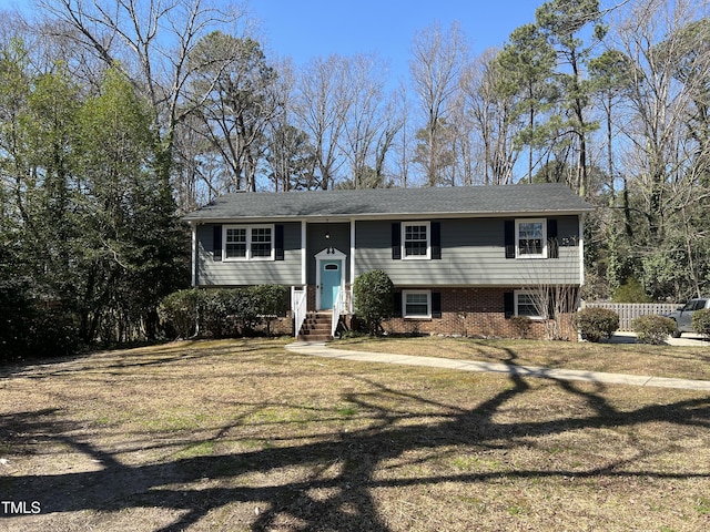 bi-level home with brick siding, a front lawn, and fence