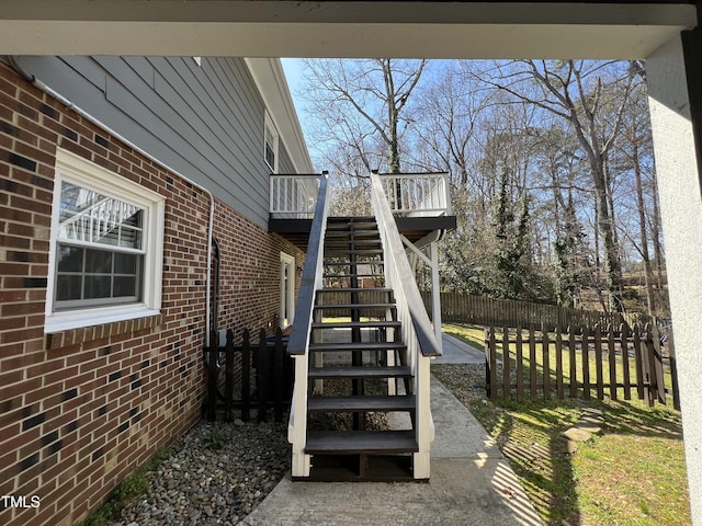 exterior space with stairway, brick siding, and fence