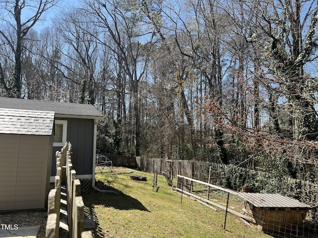 view of yard featuring an outbuilding, a storage unit, and fence