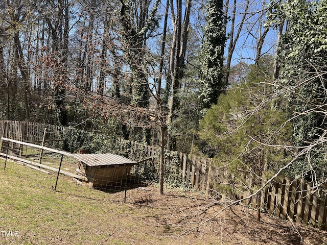 view of yard featuring an outbuilding, fence, and a forest view