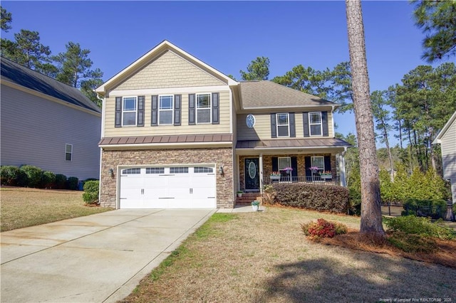 craftsman-style home featuring a front lawn, a porch, a garage, stone siding, and driveway