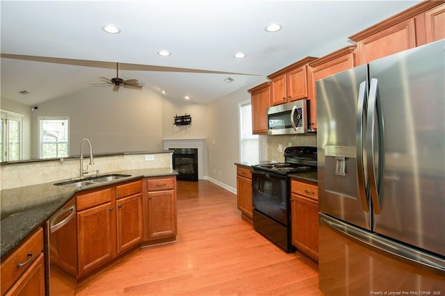 kitchen with a ceiling fan, light wood-style flooring, a sink, stainless steel appliances, and brown cabinets