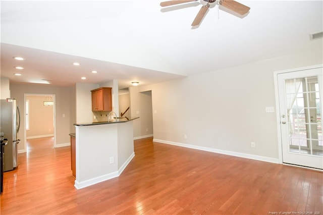 kitchen featuring light wood finished floors, freestanding refrigerator, a ceiling fan, and vaulted ceiling