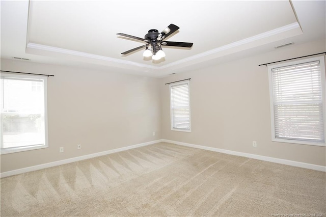 unfurnished room with baseboards, a tray ceiling, ornamental molding, light carpet, and a ceiling fan