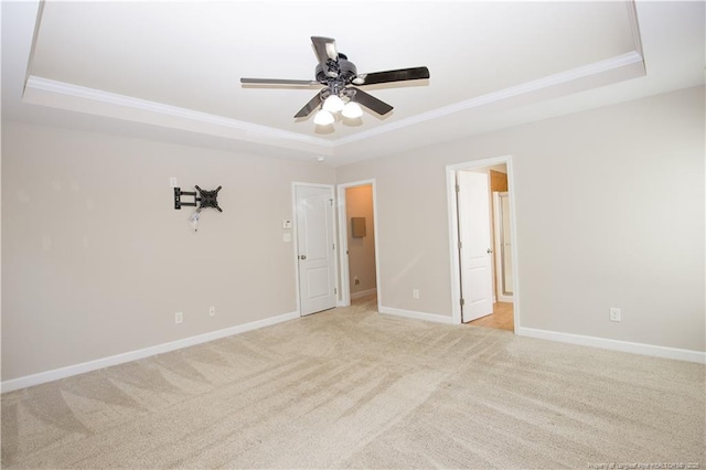 spare room featuring ceiling fan, baseboards, a tray ceiling, and ornamental molding