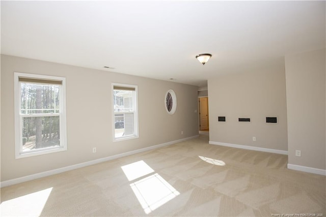 unfurnished room featuring baseboards, a wealth of natural light, and light carpet