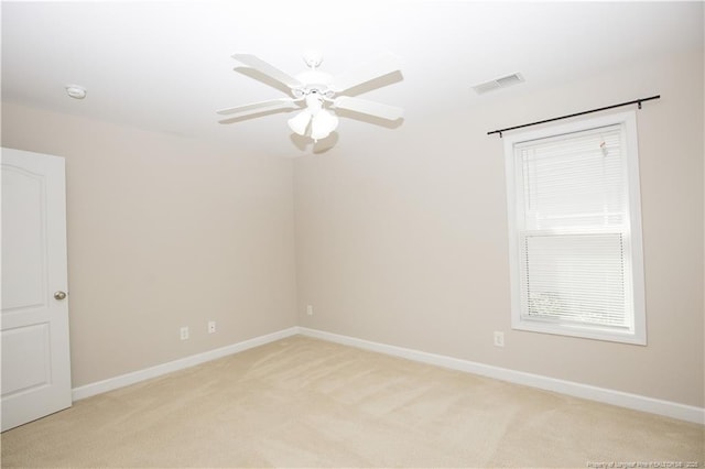 spare room with baseboards, a ceiling fan, visible vents, and light carpet