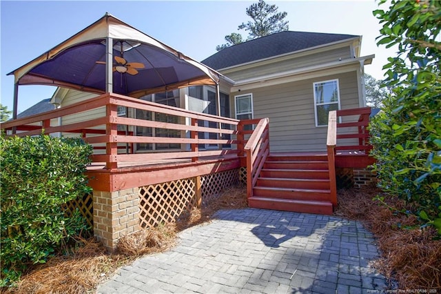 rear view of house featuring a shingled roof, a deck, and a ceiling fan