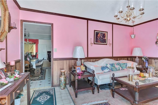 living room with a wainscoted wall, a notable chandelier, and ornamental molding