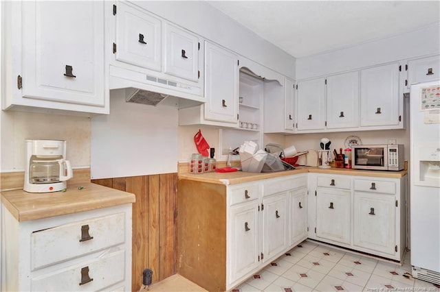 kitchen with light countertops, white cabinets, white refrigerator with ice dispenser, under cabinet range hood, and stainless steel microwave