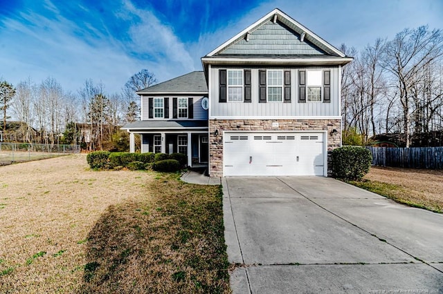 view of front of property featuring driveway, stone siding, fence, a front yard, and an attached garage