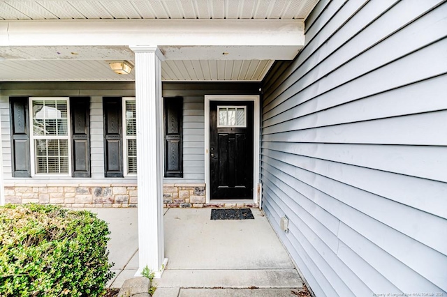 entrance to property featuring a porch and stone siding