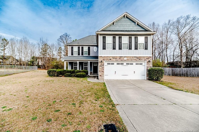 view of front facade with a front yard, fence, concrete driveway, a garage, and stone siding