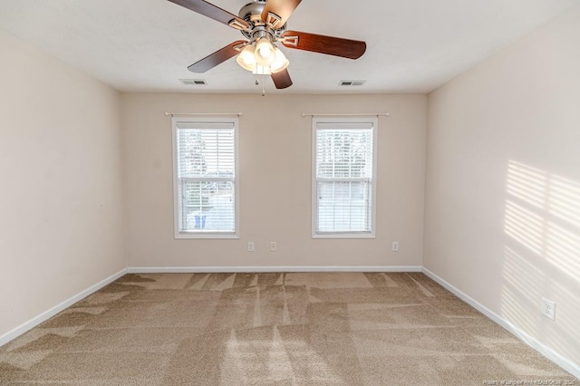 carpeted spare room with baseboards, visible vents, and ceiling fan