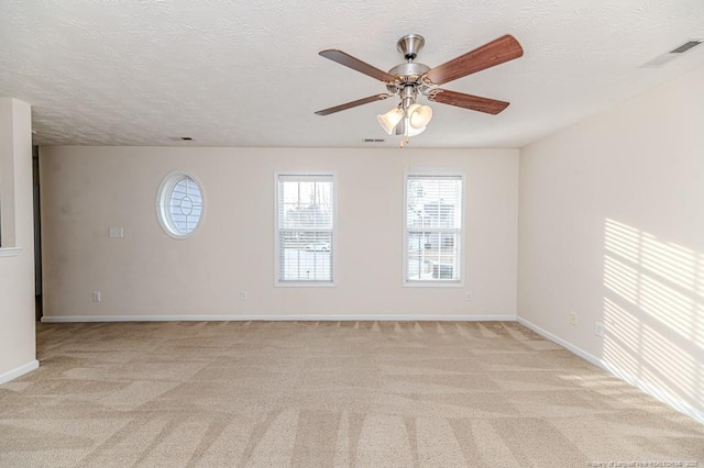 spare room with visible vents, baseboards, ceiling fan, a textured ceiling, and light carpet