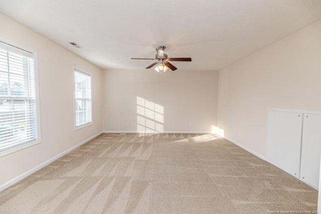 spare room with baseboards, light carpet, and a ceiling fan