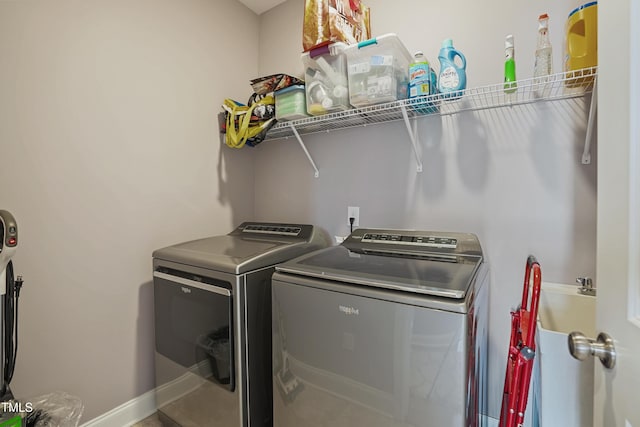 clothes washing area featuring laundry area, washer and dryer, and baseboards