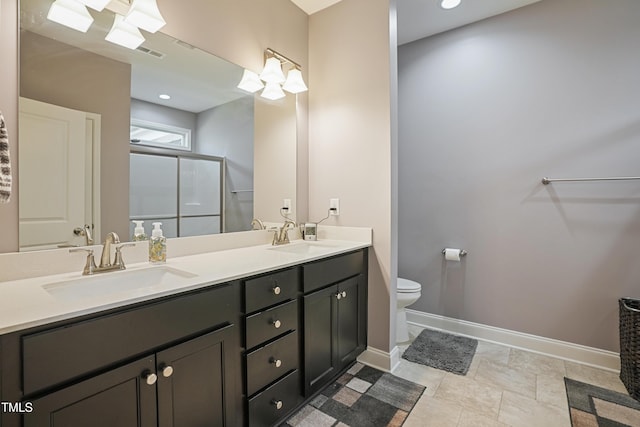 full bath with baseboards, double vanity, a stall shower, a sink, and toilet