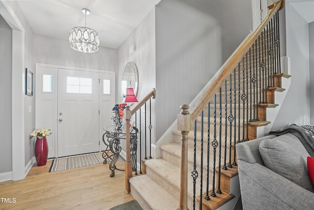 foyer featuring stairway, baseboards, a notable chandelier, and wood finished floors