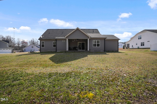 rear view of property with a ceiling fan and a yard