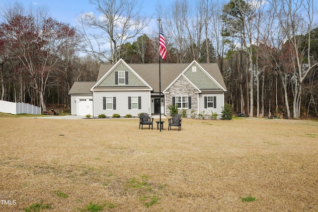 view of front of property with a front lawn, an attached garage, fence, and stone siding