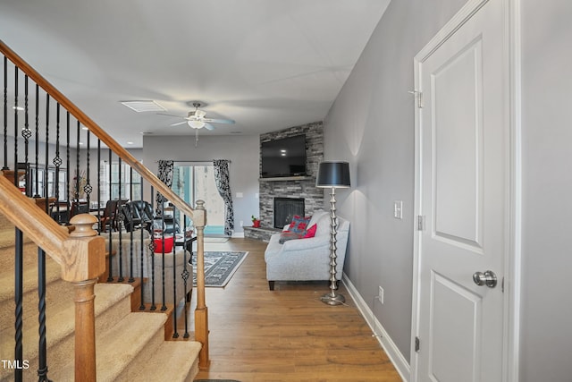 living room with baseboards, stairway, a fireplace, wood finished floors, and a ceiling fan