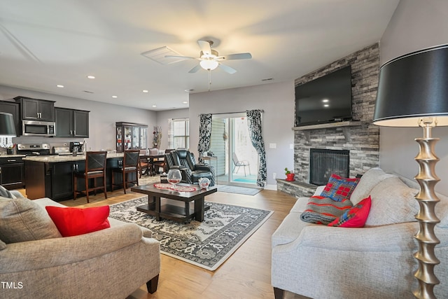 living room featuring light wood finished floors, baseboards, recessed lighting, a fireplace, and a ceiling fan