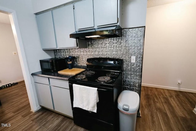 kitchen featuring black appliances, under cabinet range hood, dark countertops, dark wood finished floors, and decorative backsplash