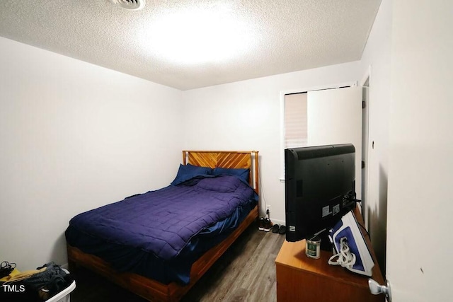 bedroom featuring a textured ceiling and wood finished floors