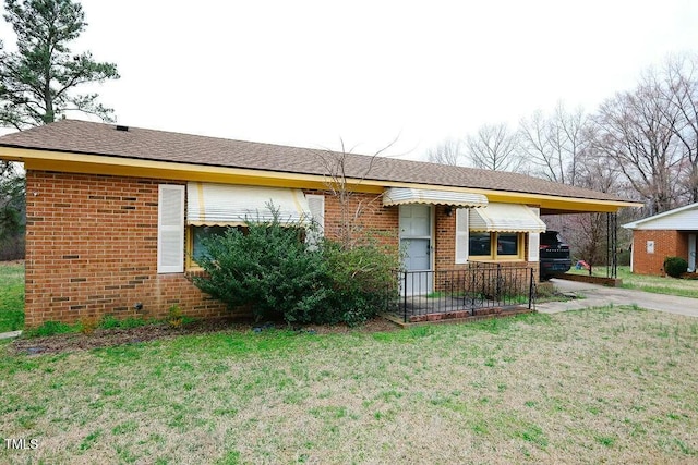 ranch-style home with an attached carport, concrete driveway, brick siding, and a front lawn