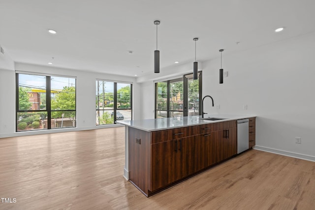 kitchen with a peninsula, open floor plan, light wood finished floors, and a sink