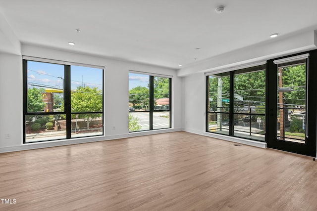 unfurnished room featuring a wealth of natural light, baseboards, wood finished floors, and recessed lighting