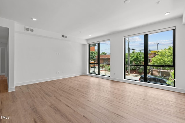 empty room with recessed lighting, wood finished floors, visible vents, and baseboards