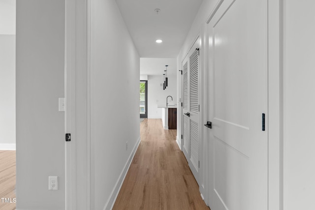 hall with baseboards and light wood finished floors