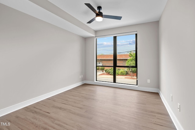 empty room featuring light wood finished floors, a ceiling fan, and baseboards