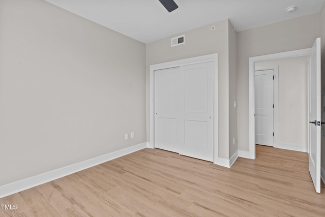 unfurnished bedroom with a ceiling fan, baseboards, visible vents, light wood finished floors, and a closet