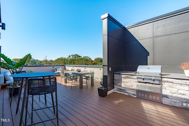 wooden terrace featuring area for grilling, an outdoor kitchen, and outdoor dining area