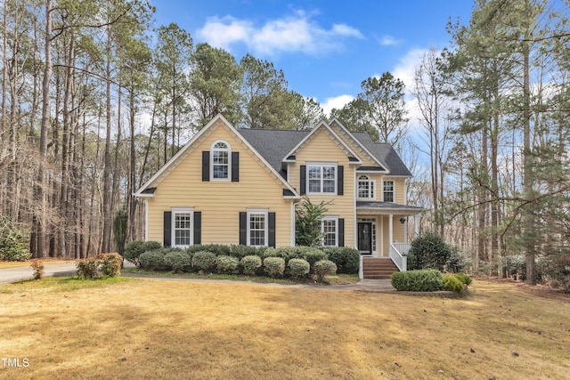 view of front of home featuring a shingled roof and a front yard