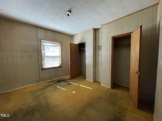 990 County Home Rd, Blanch, NC 27212 - unfurnished bedroom with wood walls, multiple closets, and carpet