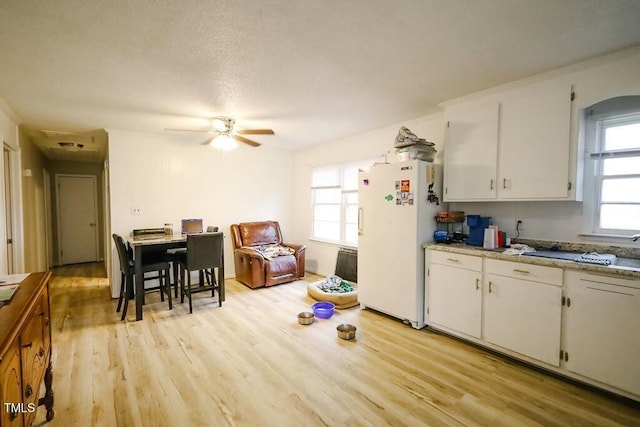 kitchen with freestanding refrigerator, white cabinets, light wood finished floors, ceiling fan, and light countertops