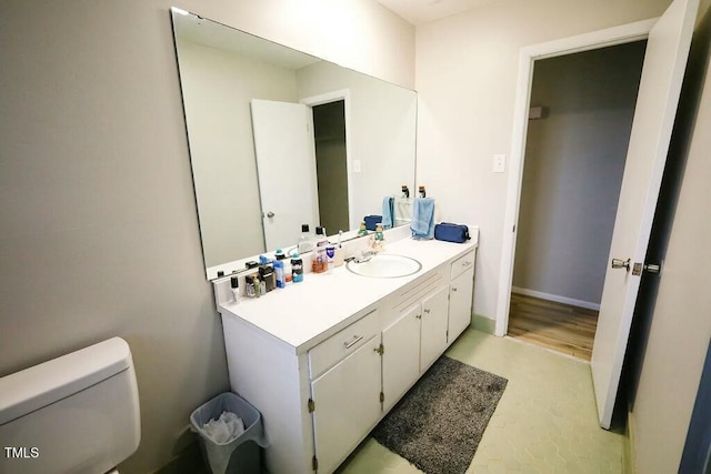 bathroom with toilet, vanity, and baseboards