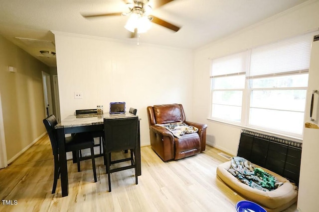 dining space featuring light wood-style flooring, baseboards, crown molding, and a ceiling fan