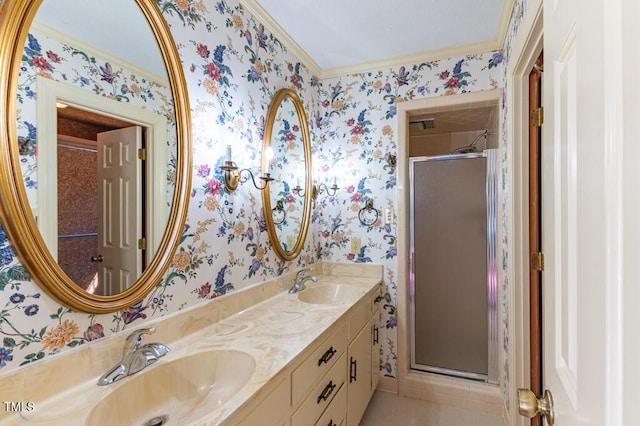 bathroom with double vanity, a stall shower, wallpapered walls, and a sink