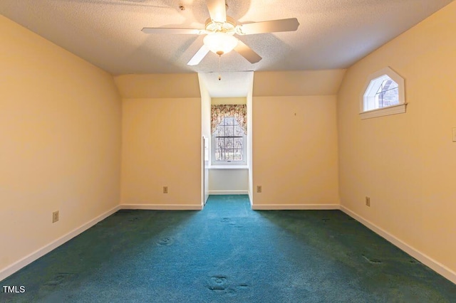 interior space featuring a ceiling fan, baseboards, vaulted ceiling, a textured ceiling, and carpet flooring