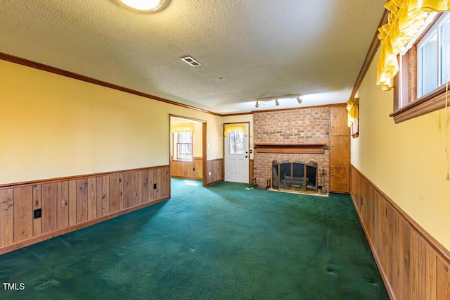 unfurnished living room with visible vents, wainscoting, and a textured ceiling