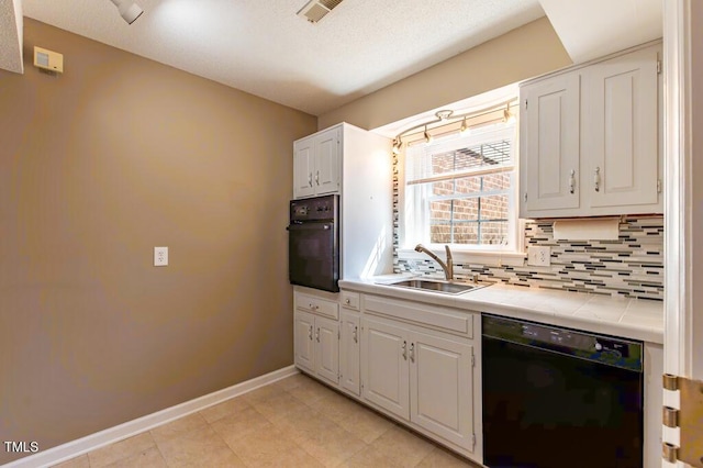 kitchen featuring visible vents, black appliances, a sink, tasteful backsplash, and tile countertops