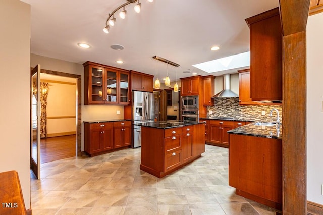 kitchen with a kitchen island, a skylight, stainless steel appliances, wall chimney exhaust hood, and a sink