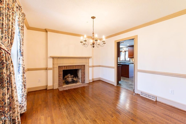 unfurnished living room with wood finished floors, baseboards, visible vents, crown molding, and a chandelier